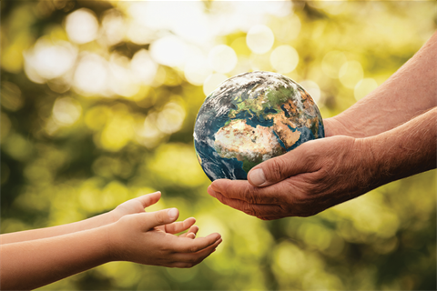 Adult hands holding world globe passing to small childs hands