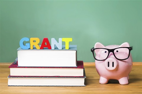 Piggy bank with stack of books with word GRANT on top