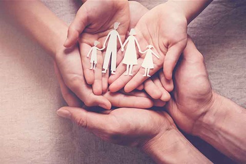 Hands linked holding paper cut out of traditional family