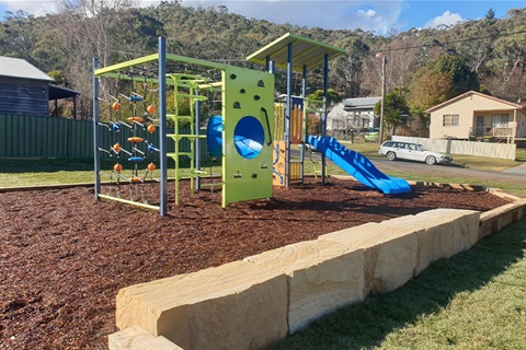 Colourful green and blue playground with climbing equipment and slide