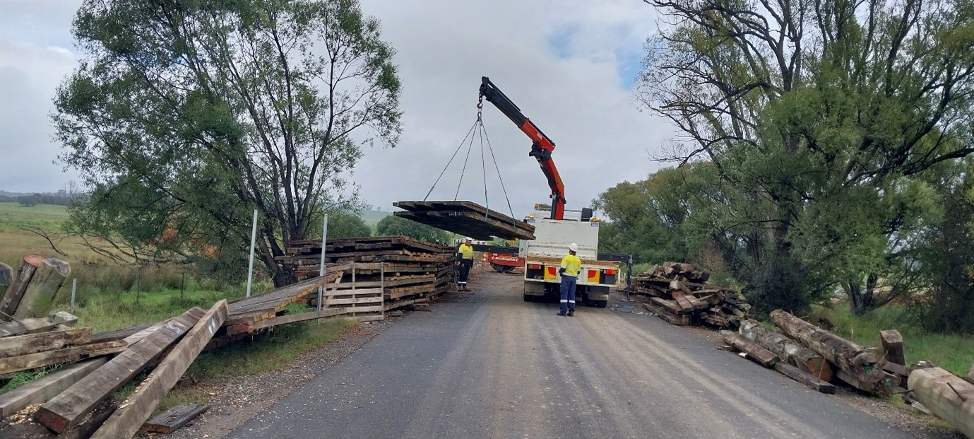 Truck with crane lifting bridge timbers
