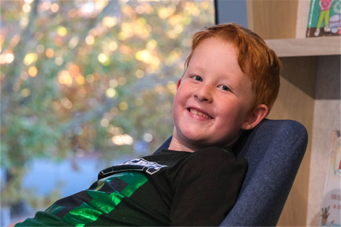 Young boy sitting on a chair and smiling at the camera